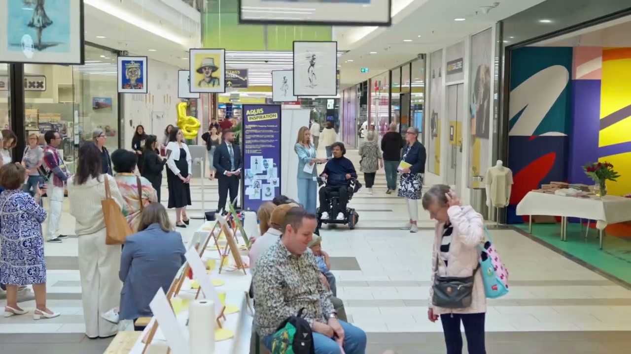 AQUIS-INSPIRATION-Ausstellung mit Kunstwerken, Besuchern und Workshop-Tischen im Atrium